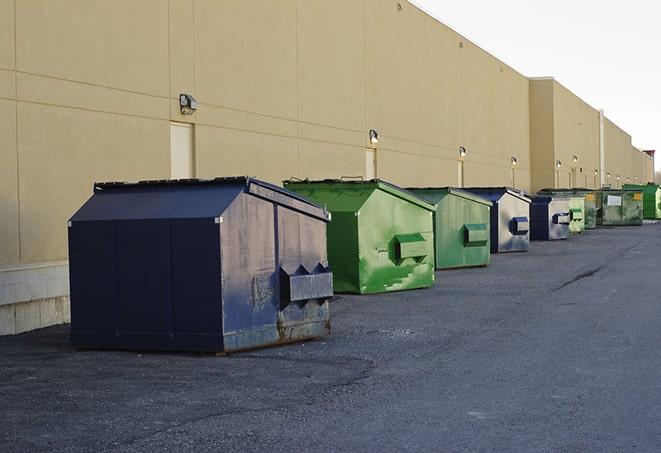 a construction worker unloading debris into a blue dumpster in Fort Mitchell, AL